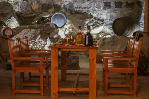a wooden table with two chairs and bottles and glasses at Yeganyans Guest House and Wine Yard in Ashtarak