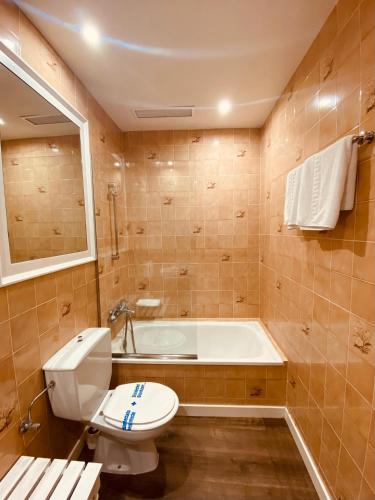 a bathroom with a toilet and a bath tub at Hotel Carbonell in Llança