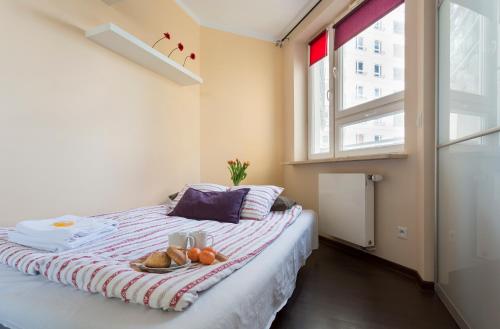 a bedroom with a bed with a plate of fruit on it at Zygmunta Slominskiego 5 - P&O Apartments in Warsaw