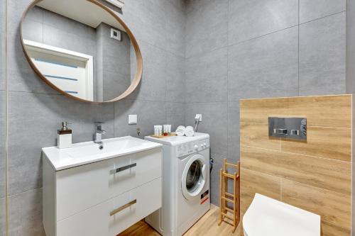a bathroom with a washing machine and a mirror at Apartament Bastion Sky Gdańsk TriApart in Gdańsk