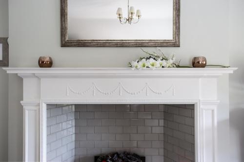 a fireplace with a white mantel with a mirror at Millbrook Lodge in Ballynahinch