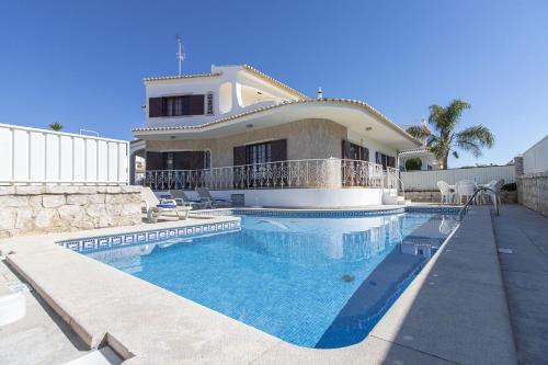 ein Haus mit einem Pool vor einem Haus in der Unterkunft Villa Brisa do Mar in Galé