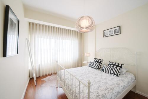 a white bedroom with a bed with black and white pillows at Apartamento Newark in Matosinhos