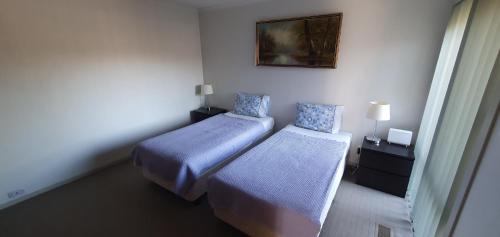 a bedroom with two beds and a picture on the wall at City Edge Lower Plenty in Lower Plenty