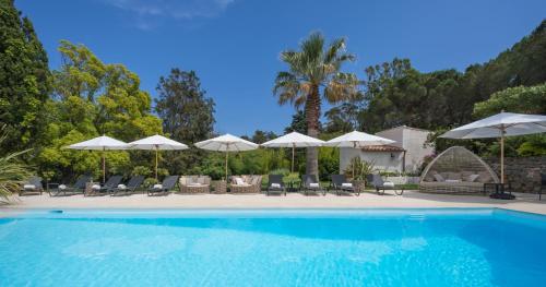 uma piscina com cadeiras e guarda-sóis em La Bastide des Salins em Saint-Tropez