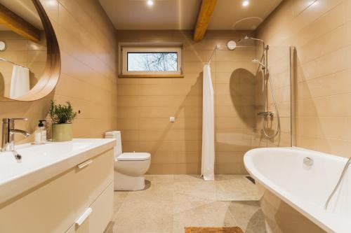 a bathroom with a tub and a toilet and a sink at Prieka Villa in Sigulda