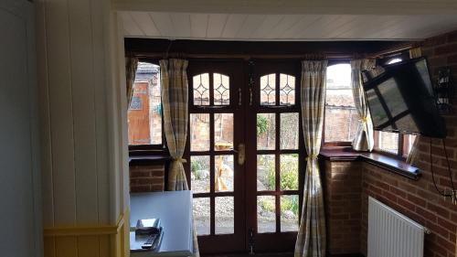 Habitación con puerta, TV y ventana. en Ruby Cottage en Irthlingborough