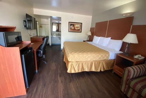 a hotel room with a bed and a desk and a television at Travelodge by Wyndham Albuquerque West in Albuquerque