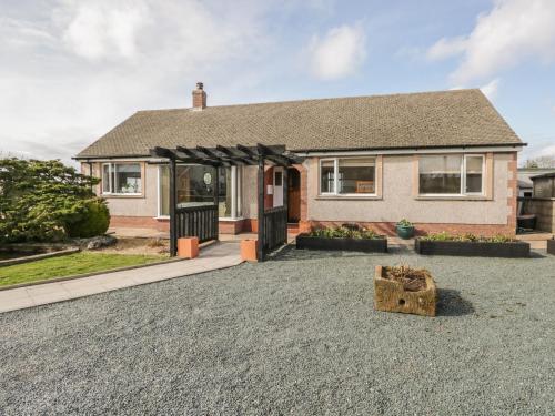a house with a gravel driveway in front of it at The Croft Bungalow in Wigton