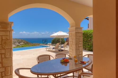 a patio with a table and chairs and the ocean at Aphrodite Hills Rentals - Junior Villas in Kouklia