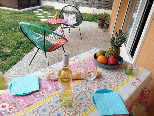 una mesa con una botella de vino y un bol de fruta en Lovely Studio & Garden - près des plages Cagnes-sur-Mer, en Cagnes-sur-Mer