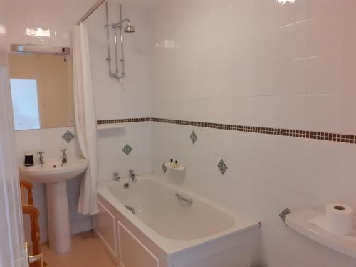 a white bathroom with a tub and a sink at 29 High Street Dunster in Minehead