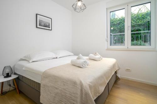 a white bedroom with two beds and a window at LUX Holiday Apartment on KASUNI Beach in Split in Split