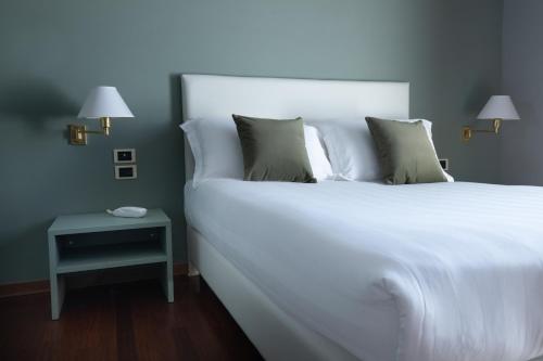 Cette chambre comprend un grand lit blanc et une table. dans l'établissement Hotel Enzo, à Porto Recanati