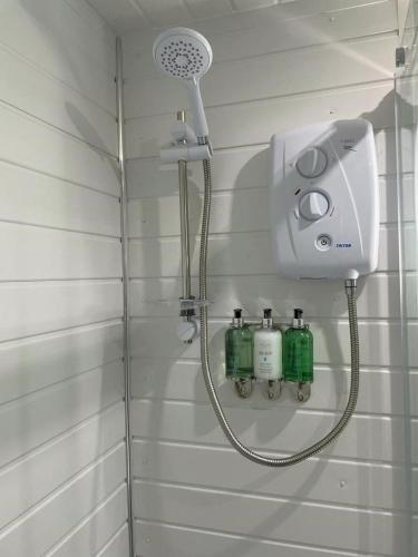 um chuveiro numa casa de banho com quatro garrafas na parede em The Old Garage em Saltdean