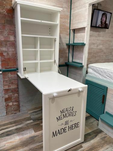 a white table with a sign on it next to a shelf at The Old Garage in Saltdean