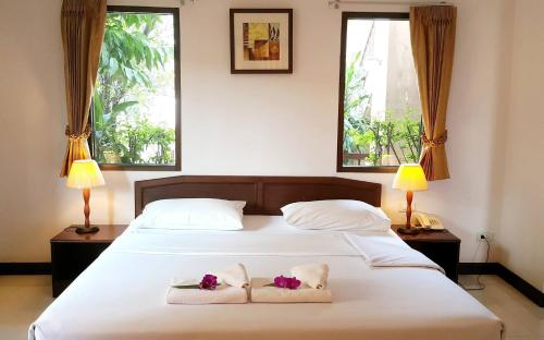 una camera da letto con un grande letto bianco con due asciugamani di โรงแรมอารีน่ารีสอร์ท อุตรดิตถ์ a Uttaradit