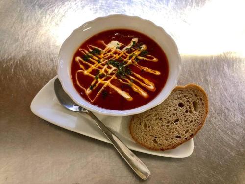 a bowl of soup on a plate with a piece of bread at MAXMILLIAN Pension & Restaurant in Mařenice