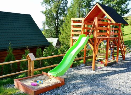 a playground with a green slide and a sandbox at Domki Górskie Zacisze in Koniaków