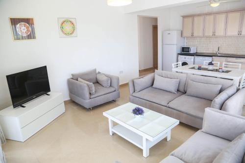 a living room with two couches and a tv at Aphrodite Beachfront Resort Official in Ghaziveran