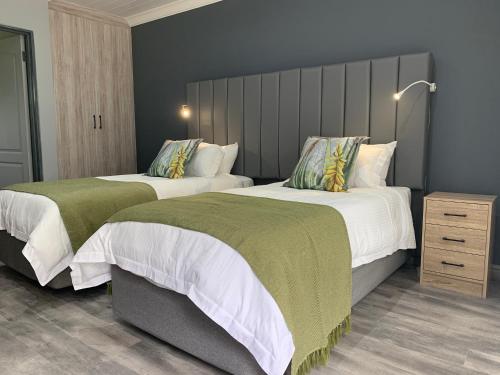 two beds with green and white sheets in a bedroom at At the River Guest House in Kroonstad
