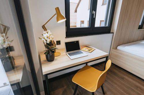 a desk with a laptop and a chair in a room at mein-schlafplatz - Leben - Arbeiten - Wohnen in Heidenheim