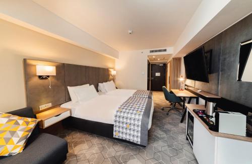 a hotel room with a large bed and a desk at Holiday Inn Bucharest - Times by IHG in Bucharest