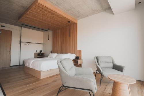 a bedroom with a bed and two chairs and a table at Atmos Hotel Boutique in Outes
