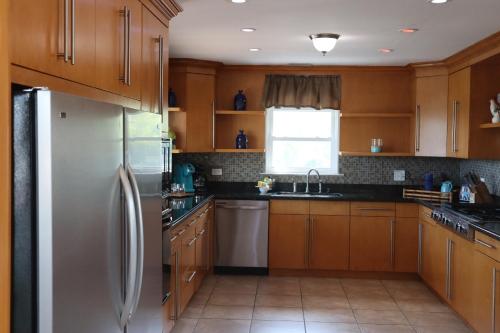 a kitchen with wooden cabinets and a stainless steel refrigerator at Tranquility in Paradise - Sugarloaf - 17 miles to Key West in Sugarloaf Shores