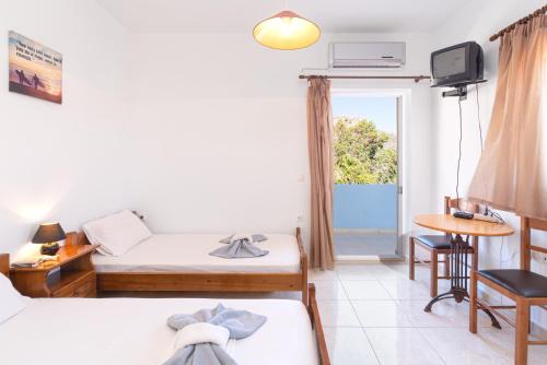 Zimmer mit 2 Betten, einem TV und einem Tisch in der Unterkunft BOGGI in Goúdhouros