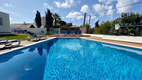 a swimming pool with chairs and a house at Galo by Check-in Portugal in Albufeira