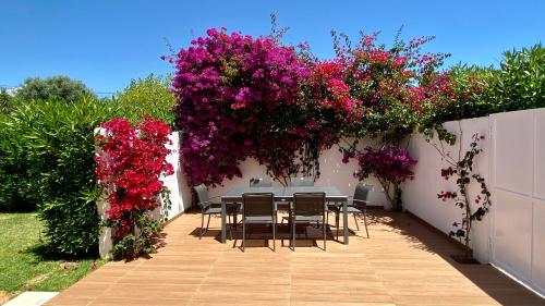 een tafel en stoelen in een tuin met roze bloemen bij Galo by Check-in Portugal in Albufeira