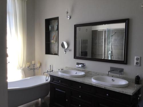 a bathroom with two sinks and a tub and a large mirror at Stunning Chateau on the river bank in Saint Astier in Saint-Astier