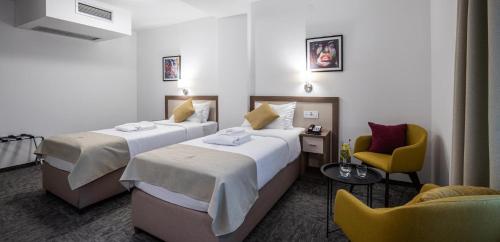 a hotel room with two beds and a chair at Hotel Fontana Vrnjačka Banja in Vrnjačka Banja