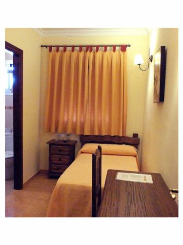 a bedroom with a bed and a wooden table at Hotel Restaurante Berlanga in Ronda