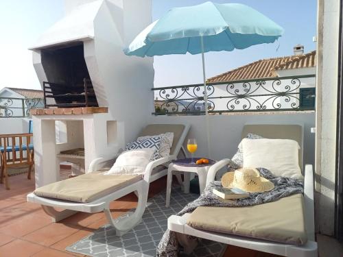 a balcony with two chairs and an umbrella at Troia Beach Getaway in Troia