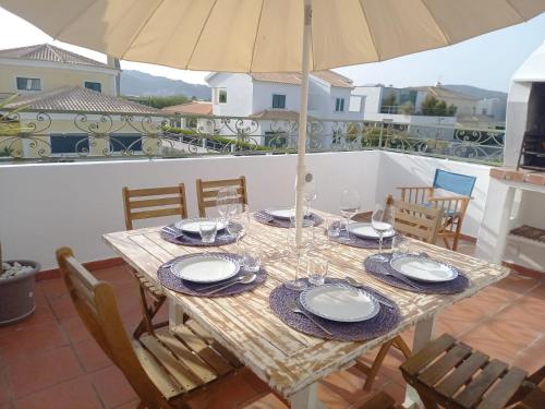 a table with chairs and an umbrella on a balcony at Troia Beach Getaway in Troia