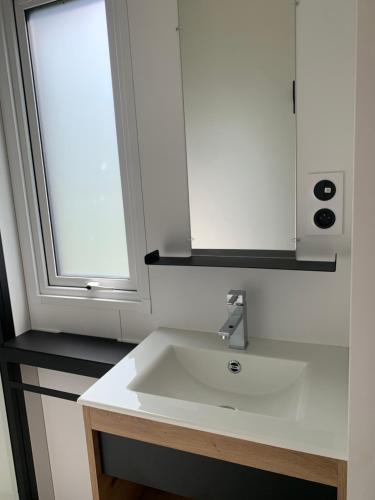 une salle de bain avec un lavabo blanc et une fenêtre dans l'établissement L'auberge du moulin des prés, à Maroilles