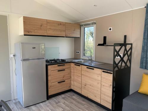 a kitchen with a white refrigerator and wooden cabinets at L'auberge du moulin des prés in Maroilles