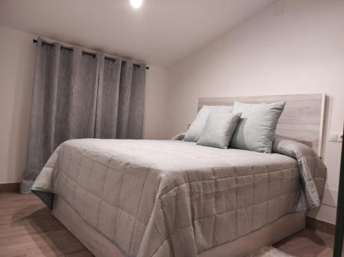 1 dormitorio con 1 cama grande con mantas y almohadas grises en Casa cueva La Tosca, en Setenil