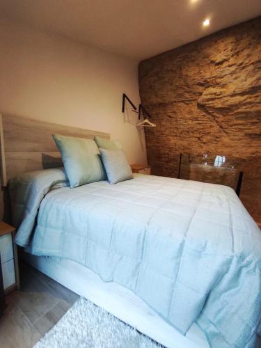 1 dormitorio con 1 cama blanca grande y pared de ladrillo en Casa cueva La Tosca en Setenil