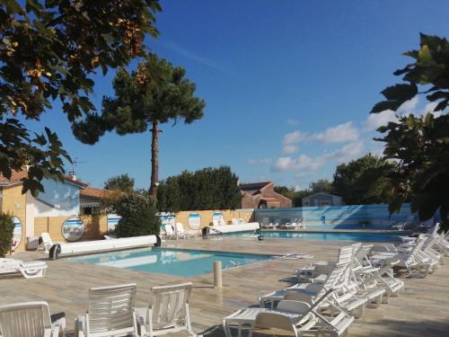 - une piscine avec des chaises blanches et un bouquet d'équipements dans l'établissement Mobilhome Oléron simple et spacieux à 1min de l'Océan, à La Cotinière