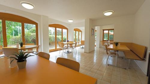 un restaurante con mesas, sillas y ventanas en Delémont Youth Hostel, en Delémont