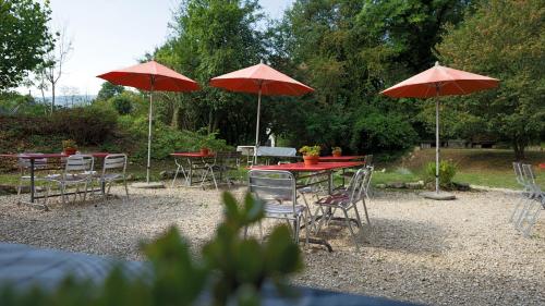 a group of tables and chairs with red umbrellas at Delémont Youth Hostel in Delémont