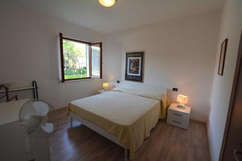 a bedroom with a bed and a window and a fan at Villa in Lignano Riviera comfortable in Lignano Sabbiadoro