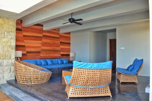a living room with wicker chairs and a blue couch at TS SUITES Seminyak Bali in Legian