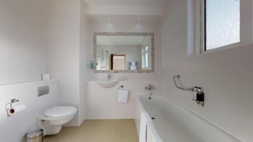 a white bathroom with a toilet and a sink at Ommaroo Hotel in Saint Helier Jersey