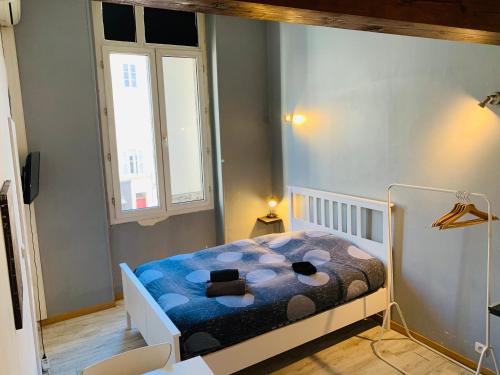 - une petite chambre avec un lit et une couverture bleue dans l'établissement Mirabeau Studio, à Aix-en-Provence