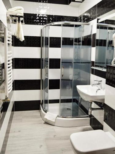 a black and white bathroom with a shower and a sink at Hotel Aquarius Restaurant Wellness Spa in Ciechocinek