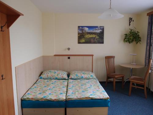 a bed in a room with a table and a chair at Penzion Cabák in Vrchlabí
